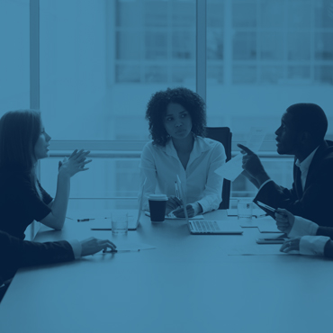 Image of three people sitting around a table at work