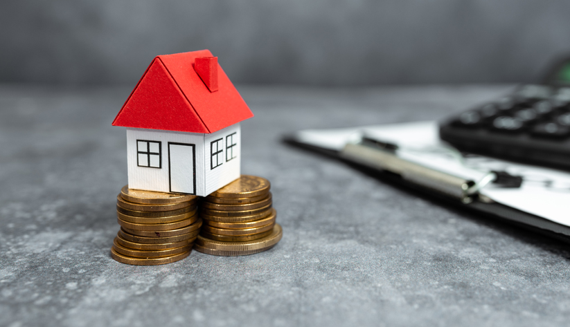 a house with a red roof sitting on top of coins