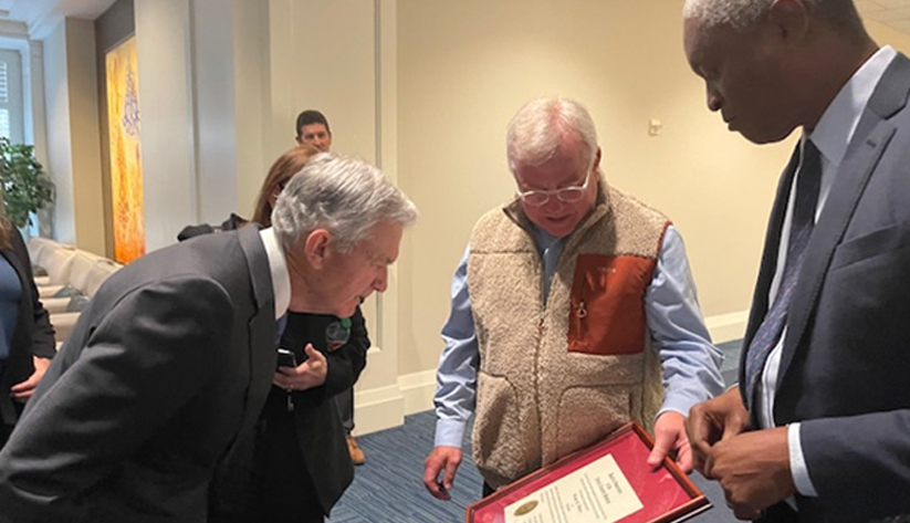Fed chair Jerome Powell and Atlanta Fed president Raphael Powell look at Greg Waters's bank examiner commission certificate.