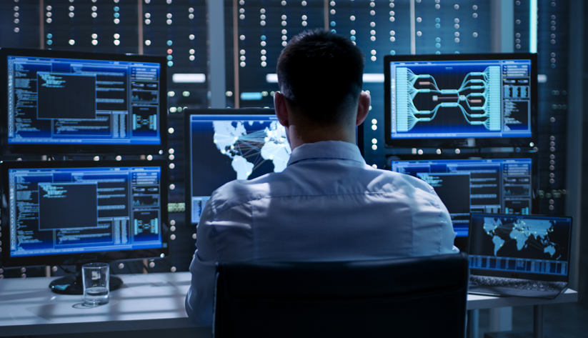 man-sitting-at-a-computer-viewing-multiple-screens