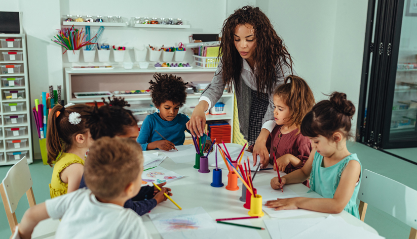 Image of children in school drawing with their teacher