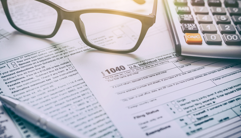 glasses and calculator resting on income tax form