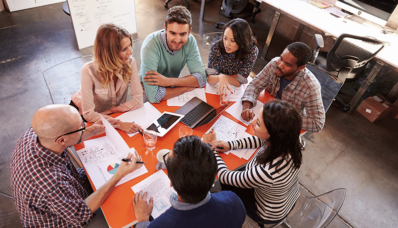 a group of diverse coworkers circled around table brainstorming 