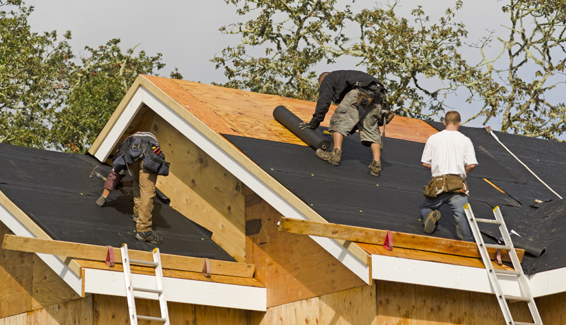 construction workers replacing roof atop structure