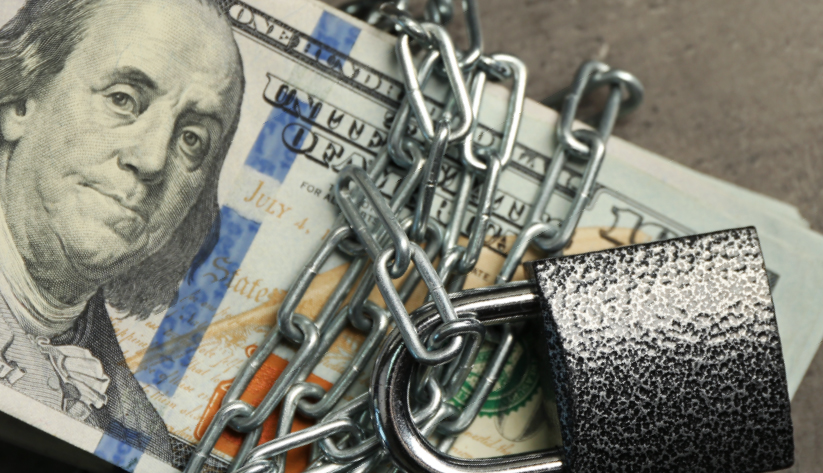 photograph of a 100-dollar bill bound with chains and a padlock