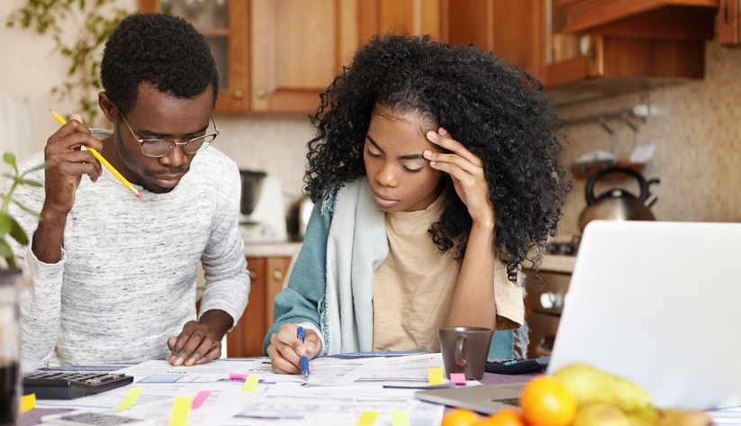 Photo of man and woman sitting at kitchen table collaborating together on a project.