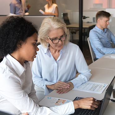 two professional women discussing work on the computer