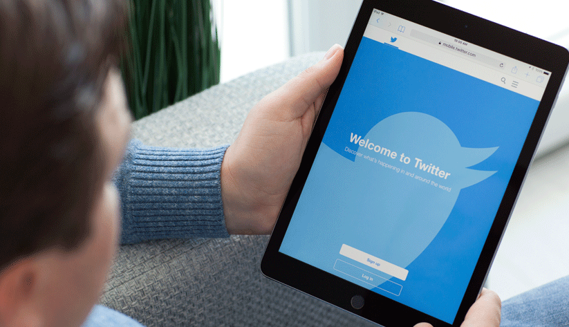 hands holding tablet displaying twitter login screen