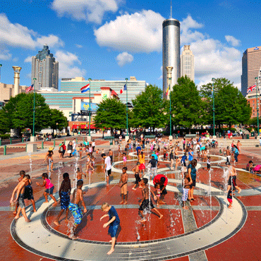 people playing in the fountains of Atlanta's Centennial Olympic Park on a bright summer day