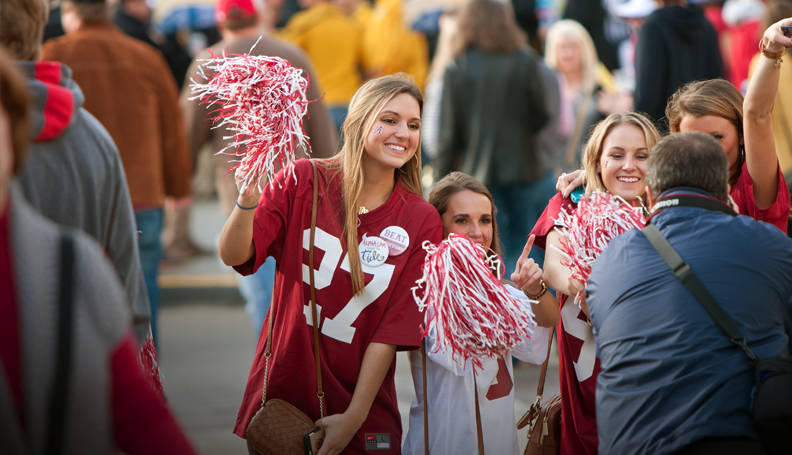 female sports fan on the sidelines of a game holding pom-poms