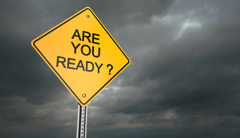 a yellow road sign reading Are You Ready? with dark storm clouds in the background