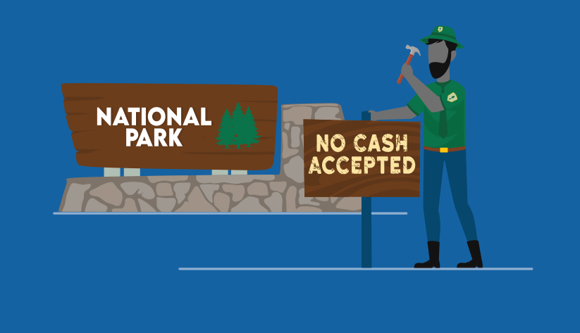 generic 'national park' sign over classic national park stone with additional sign a ranger is hammering into the ground that reads 'no cash accepted'