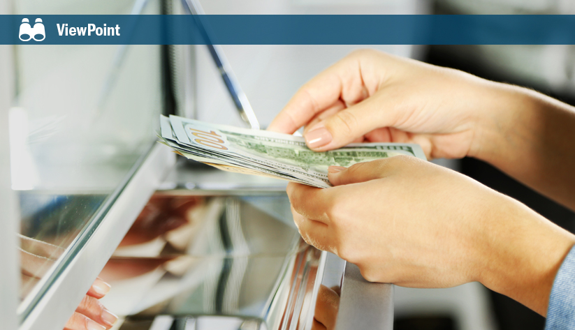 Customer receiving cash from bank teller through glass partition at counter