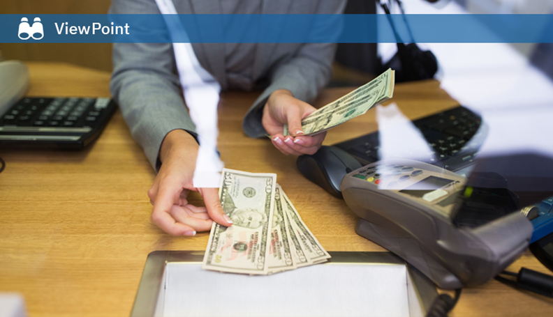 Business person in gray suit counting US dollar bills at desk with calculator and card reader