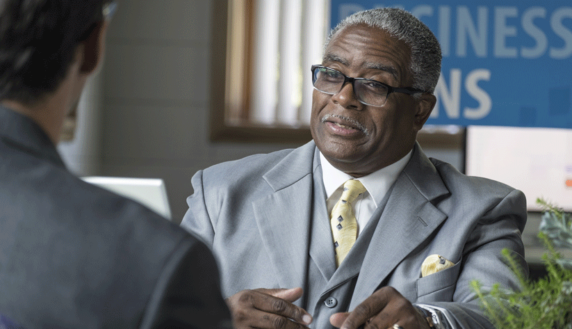 business man sitting at desk speaking to someone