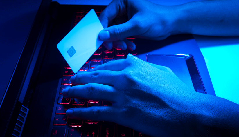 hands on computer keyboard with the other holding a credit card