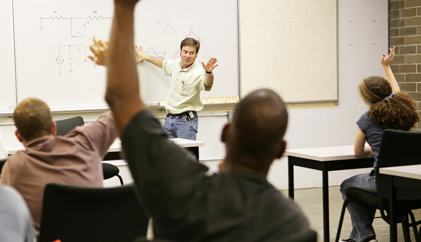 hands raised at an instructor at a whiteboard