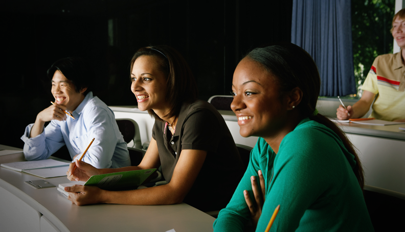 three people smiling sitting in front row of room