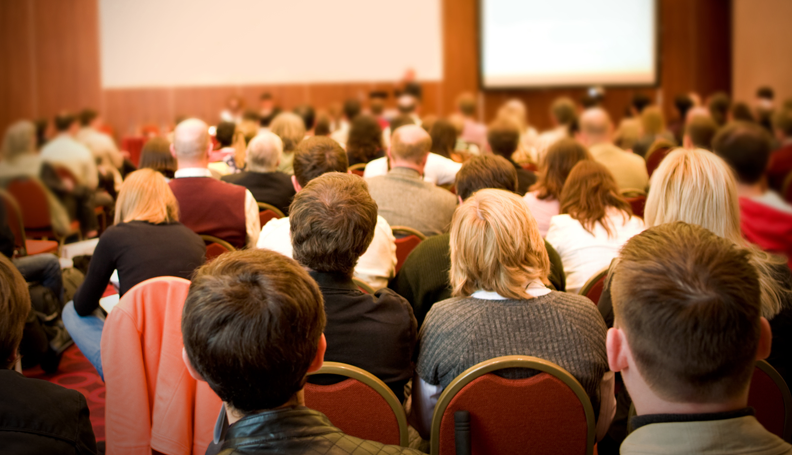 filled conference room as viewed from rear of room