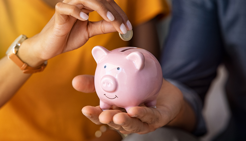 hand inserting a coin into a piggy bank