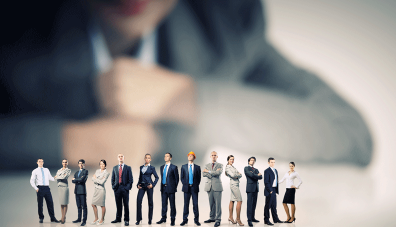 Man observing row of miniature people in business professional clothes