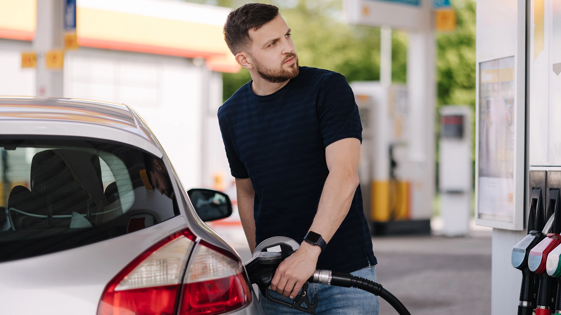 photograph of a man pumping gas while looking left