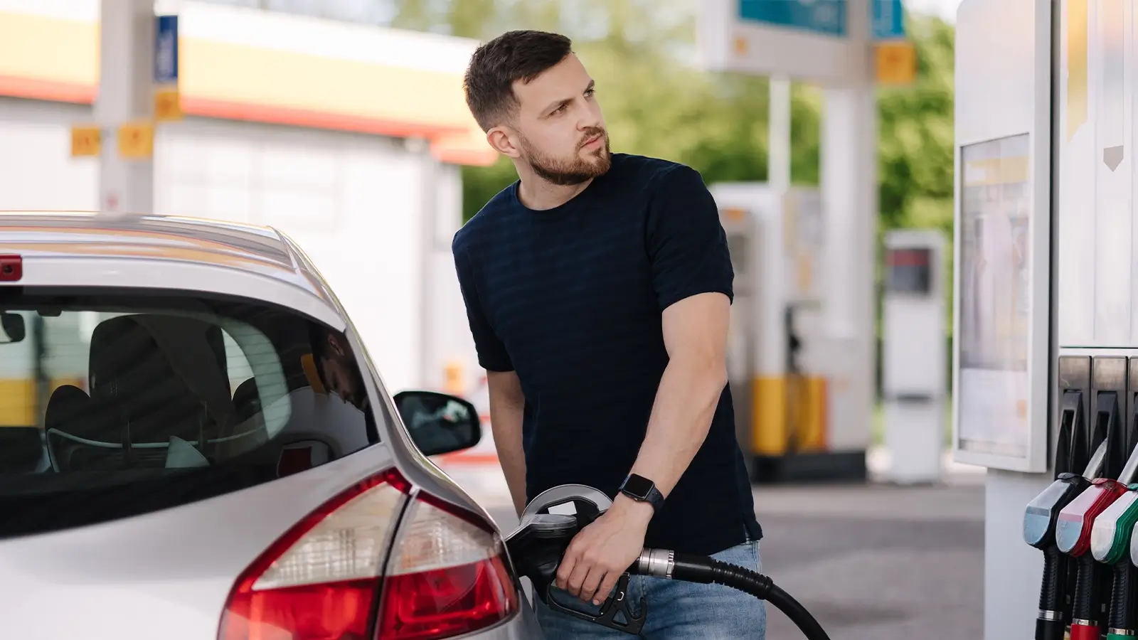 photograph of a man pumping gas while looking left