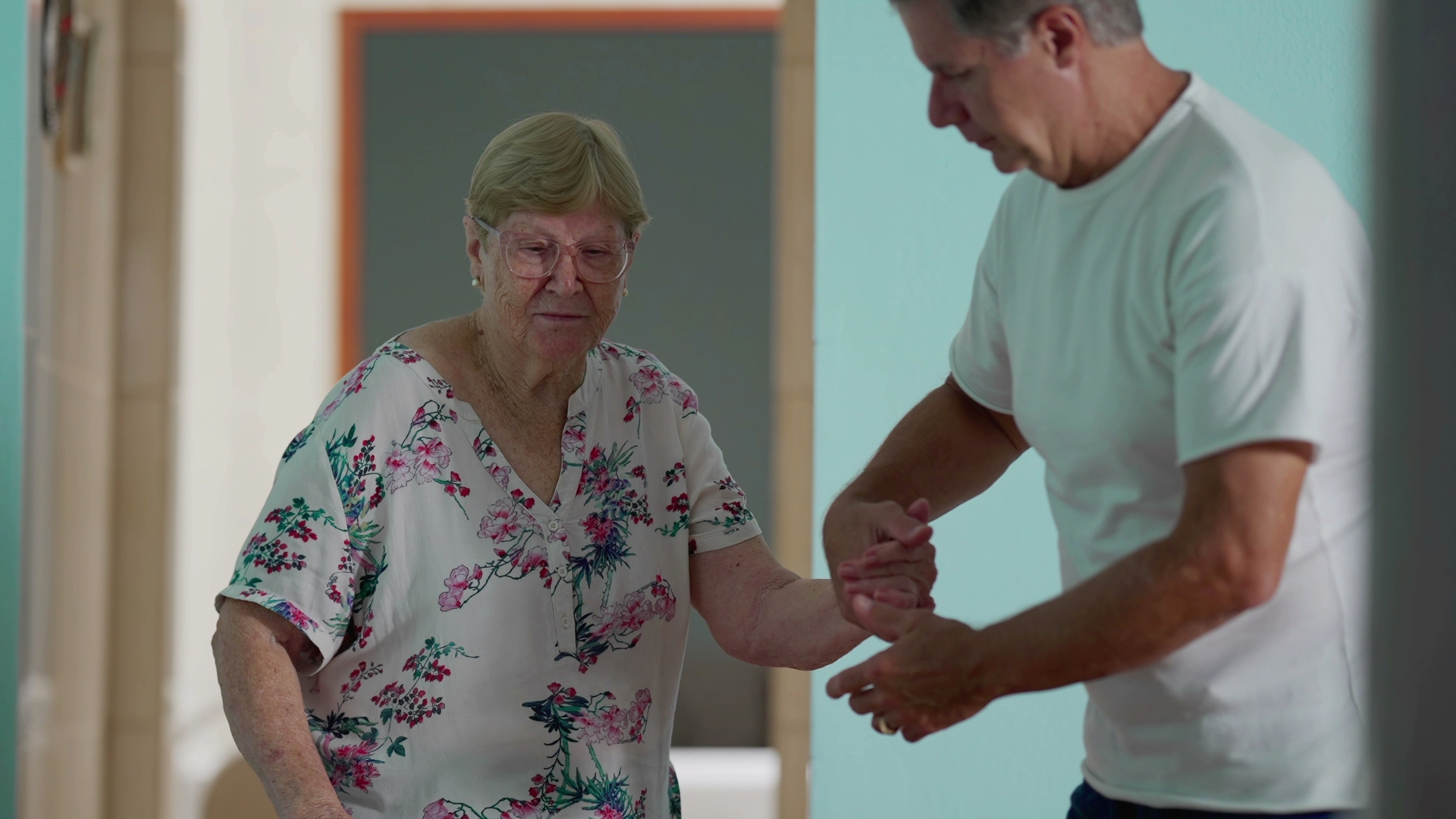 Man assisting an elderly woman walking