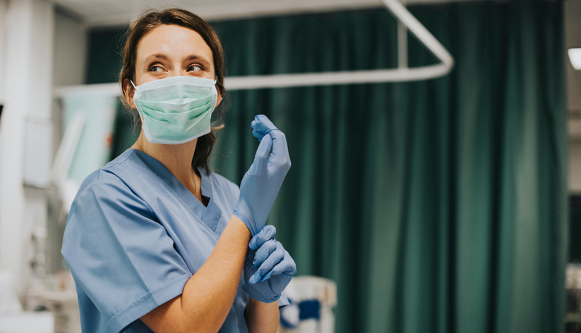 a nurse with a mask putting on gloves