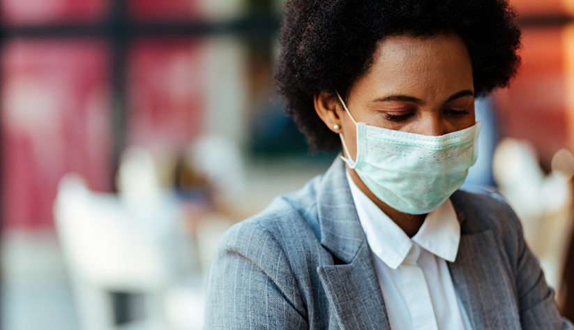 close up of woman wearing mask in pinstripe blazer looking downward