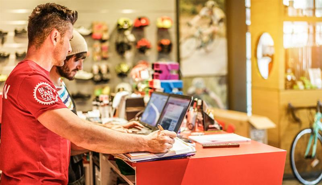 bicycle cafe manager working with employee at store computers