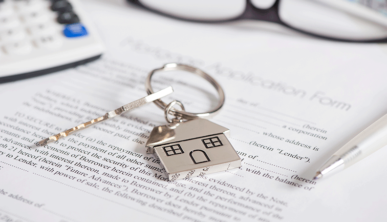 key with house charm laying over finance papers