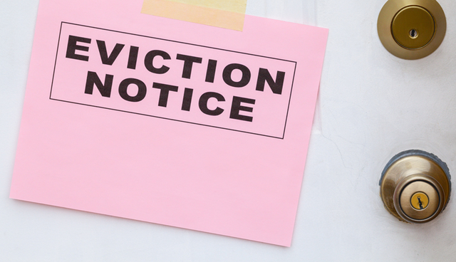 pink eviction notice taped on a white door