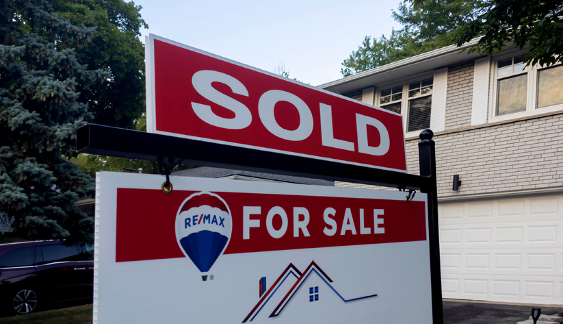 house behind with sold for sale sign in foreground