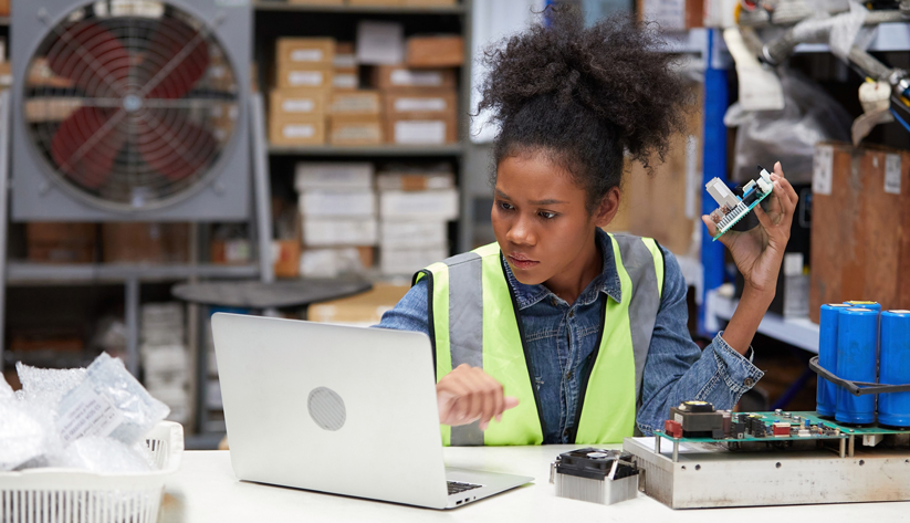 young woman looking at computer holding parts