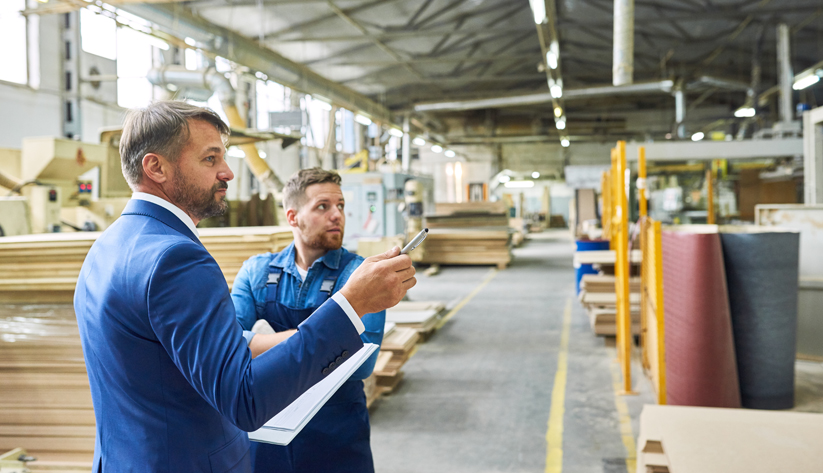 Two people standing in textile mill looking at product. 
