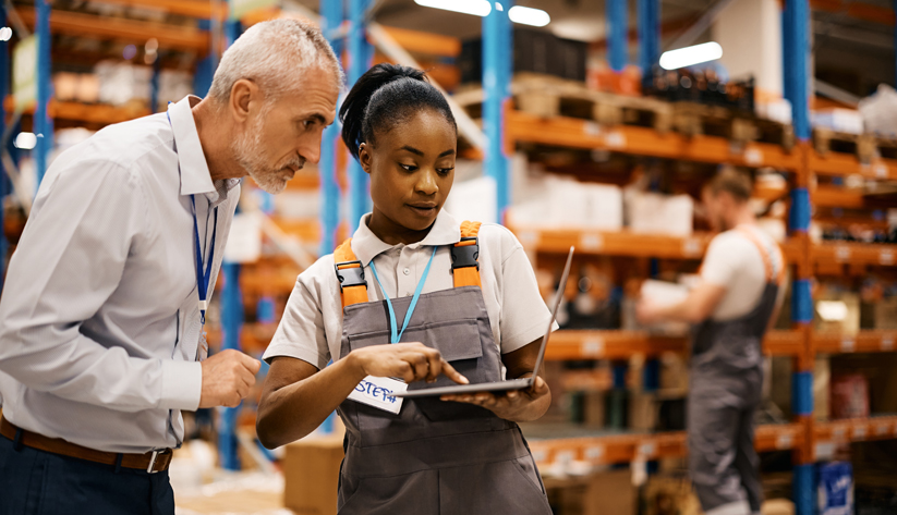 Manager and worker reviewing laptop in warehouse