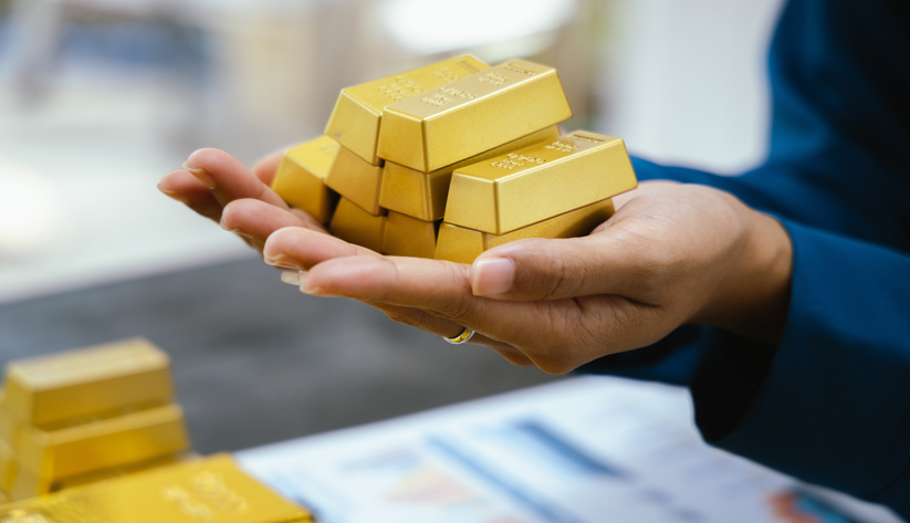 Two hands holding stacked gold bars