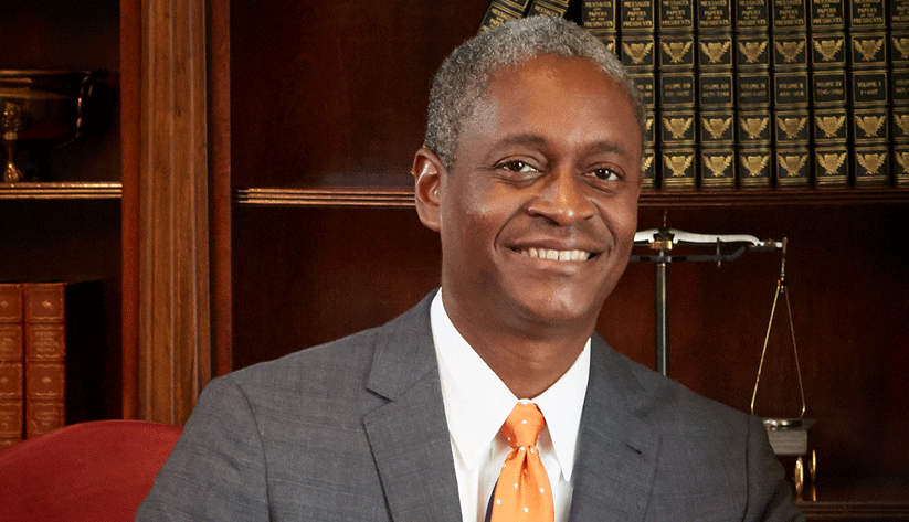 Raphael Bostic sitting in front of a bookcase.