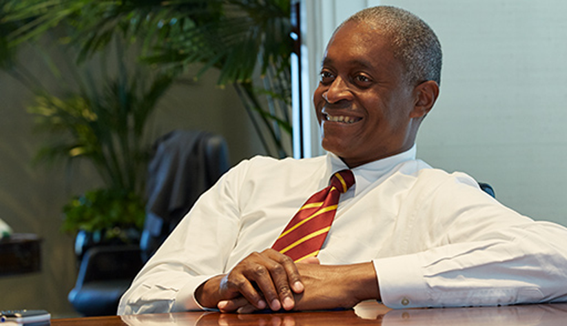 Photo of Raphael Bostic in a relaxed pose hands folded on table