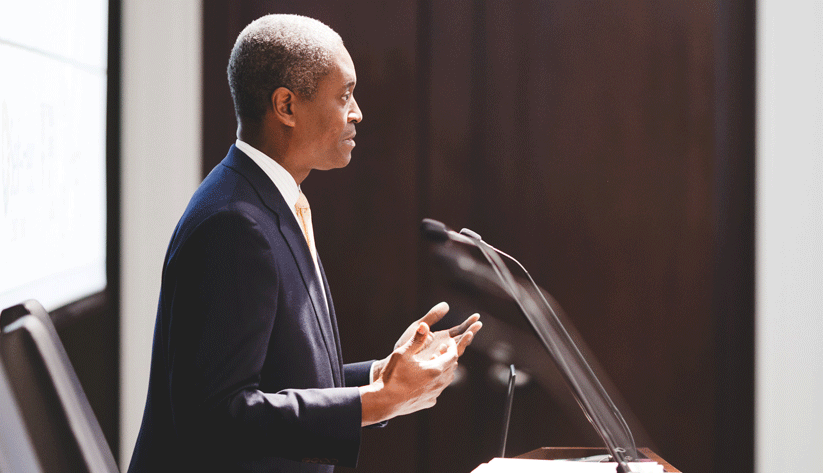 Photo of Raphael Bostic speaking at a podium as viewed from his left side profile