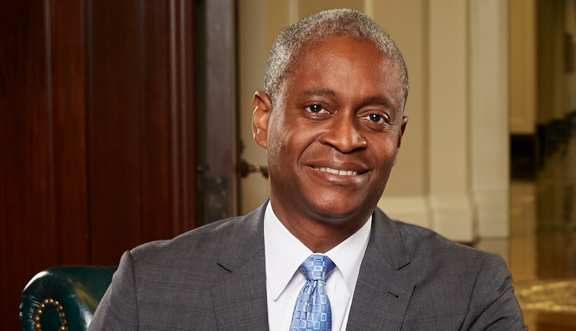 Raphael Bostic facing camera wearing grey suit with blue tie