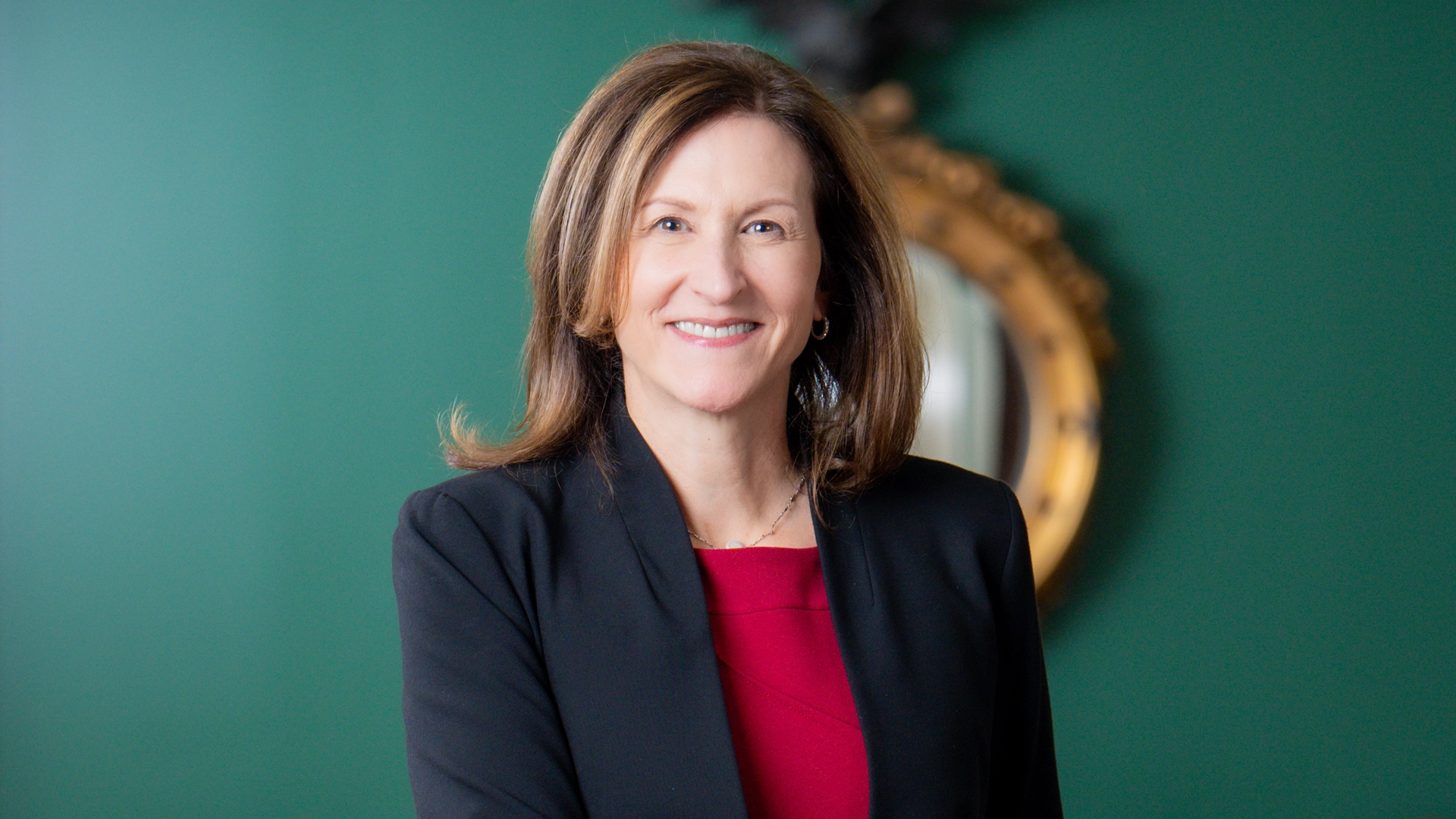 Portrait of Cheryl Venable in front of a green wall and a gold mirror
