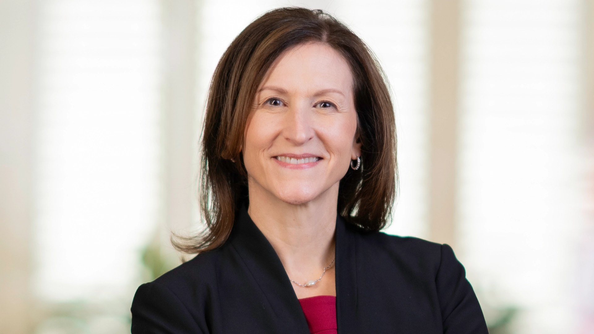 Portrait of Cheryl Venable wearing a dark blazer with red top.