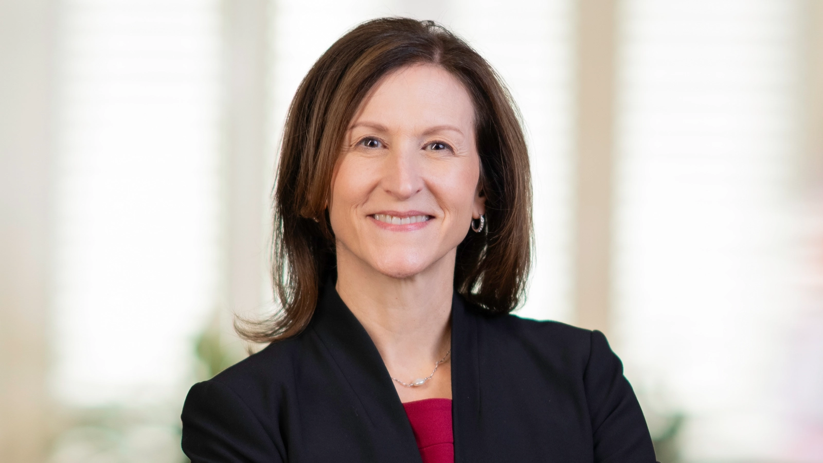 Portrait of Cheryl Venable wearing a dark blazer with red top.