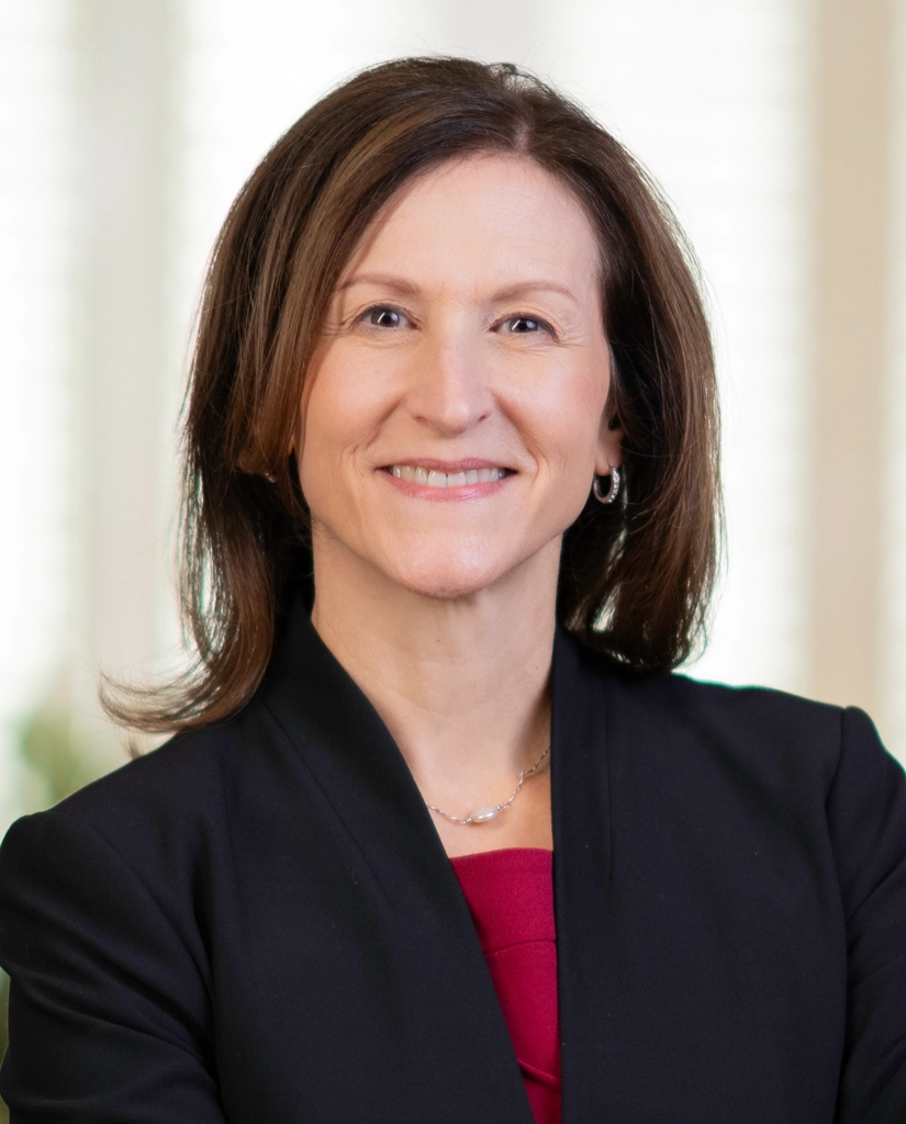 Portrait of Cheryl Venable wearing a dark blazer with red top.
