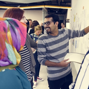 man writing on board while talking to people