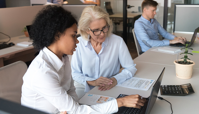 two professional women discussing work on the computer