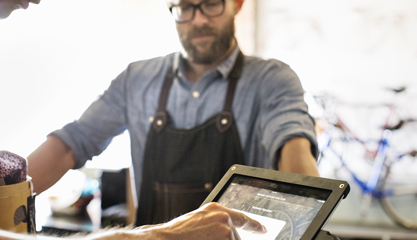 man assisting another with tablet on counter