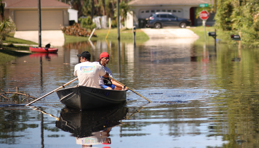 flood in neighborhood with two people on canoe